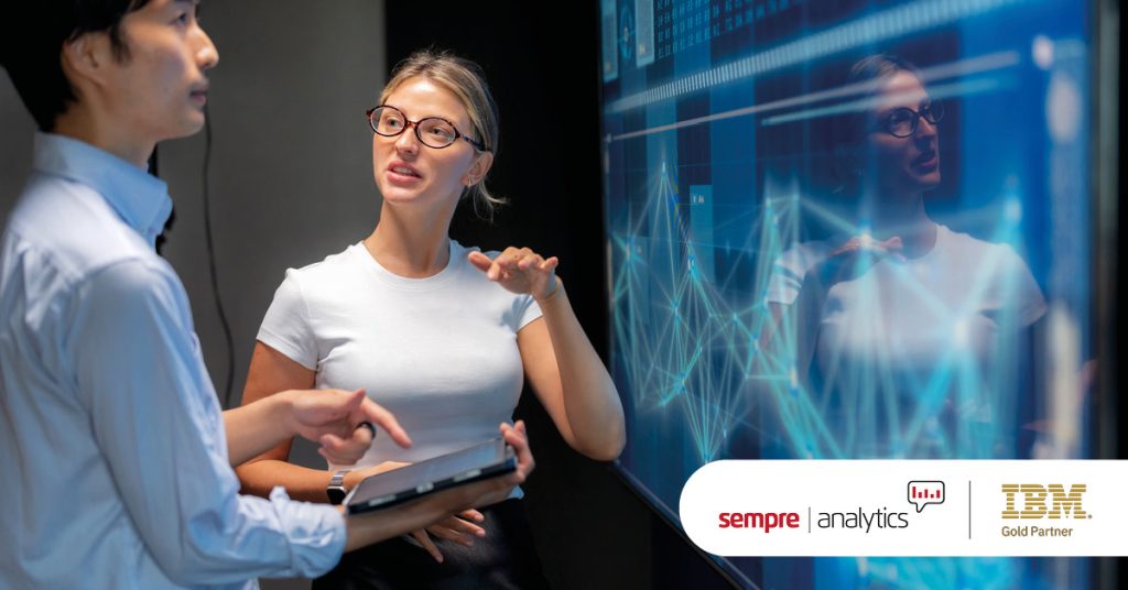 Main: Two colleagues run through data analysis on a screen. Inset: Sempre Analytics and IBM Gold Partner Logos.